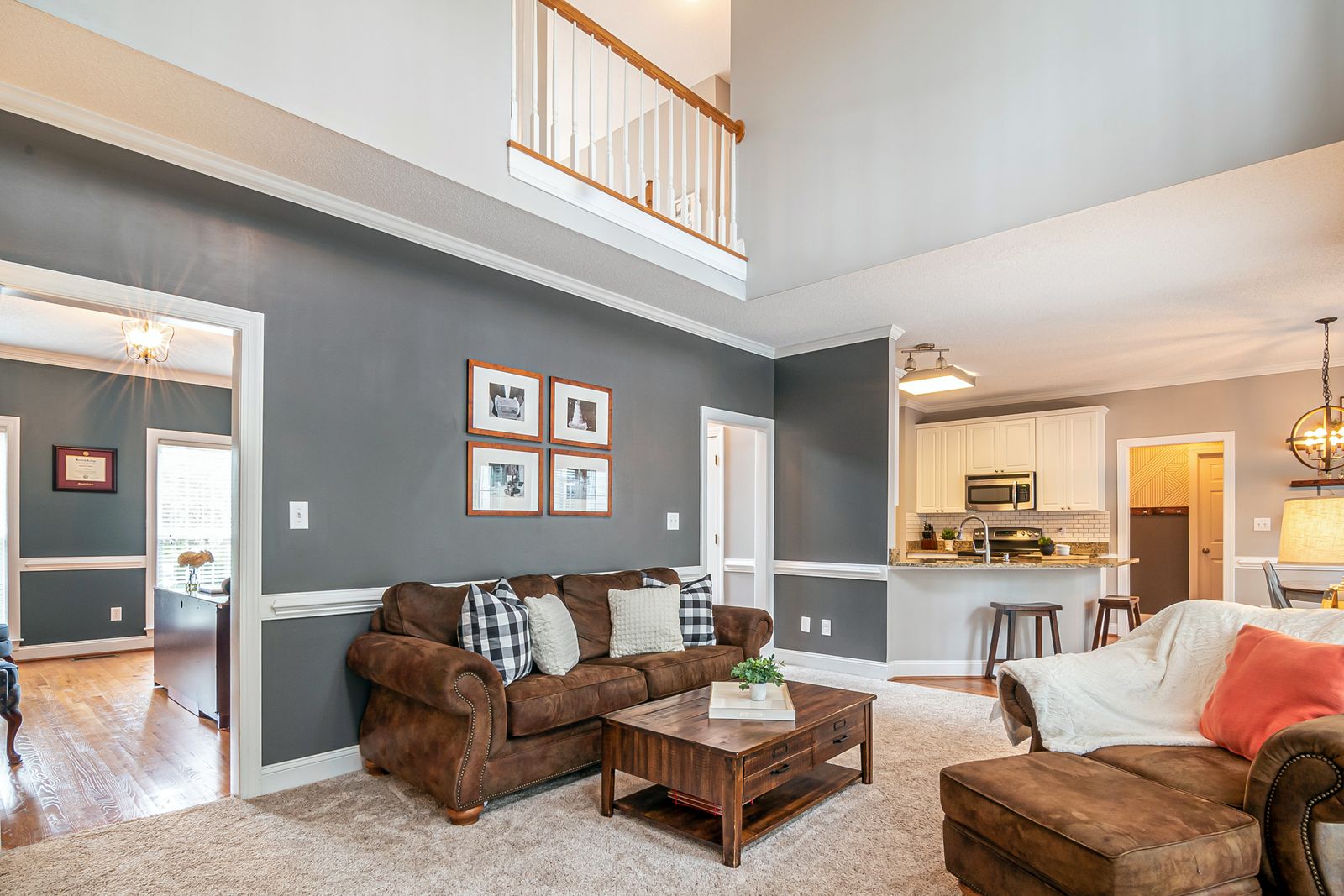 An open-plan living room with a deep brown leather sofa, checked cushions and a chunky wood coffee table.
